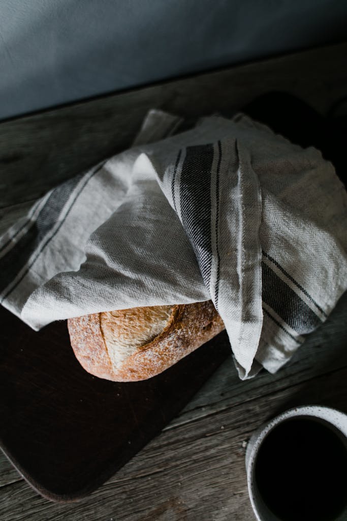 Artistic flat lay of crusty bread and black coffee on a wooden surface.