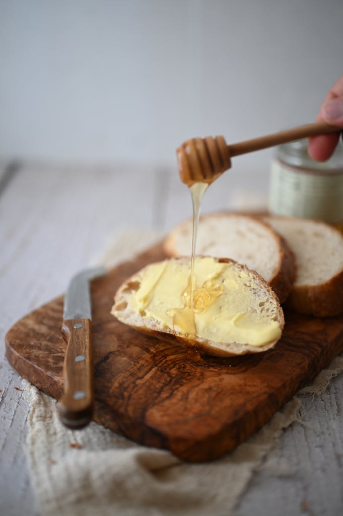 Close-up of sliced bread with butter and honey on a wooden board, creating a warm breakfast vibe.
