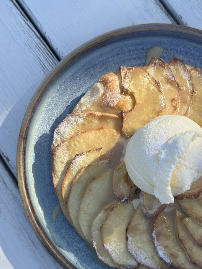 Tasty apple dessert with ice cream on a blue plate, perfect for sweet tooth cravings.