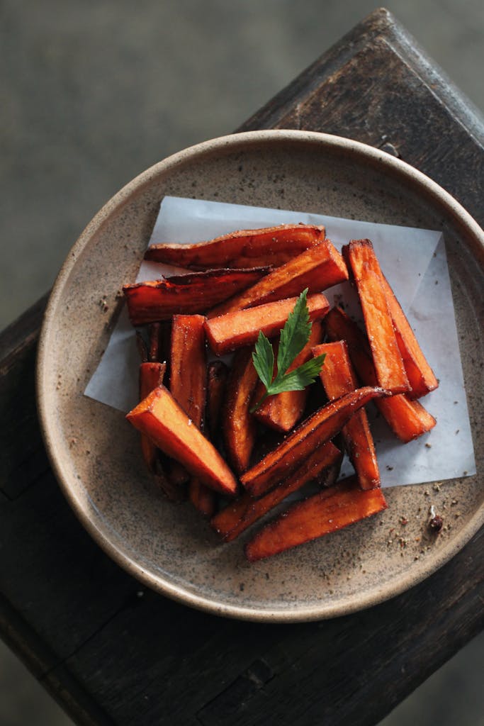 A plate of sweet potato fries garnished with herbs, perfect for a snack or side dish.
