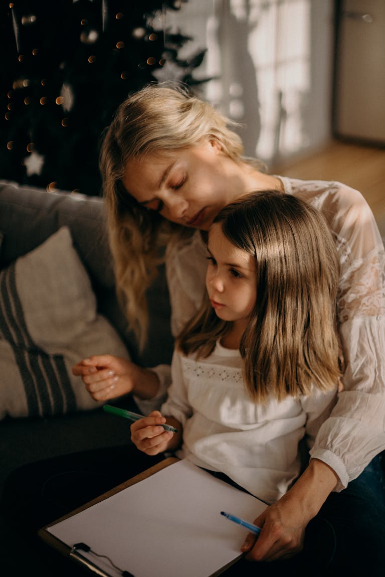 Heartwarming moment of a mother and daughter drawing together in cozy indoor setting.