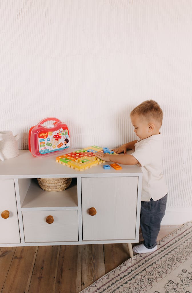 A young boy playing with an educational toy on a cabinet indoors, fostering creativity.