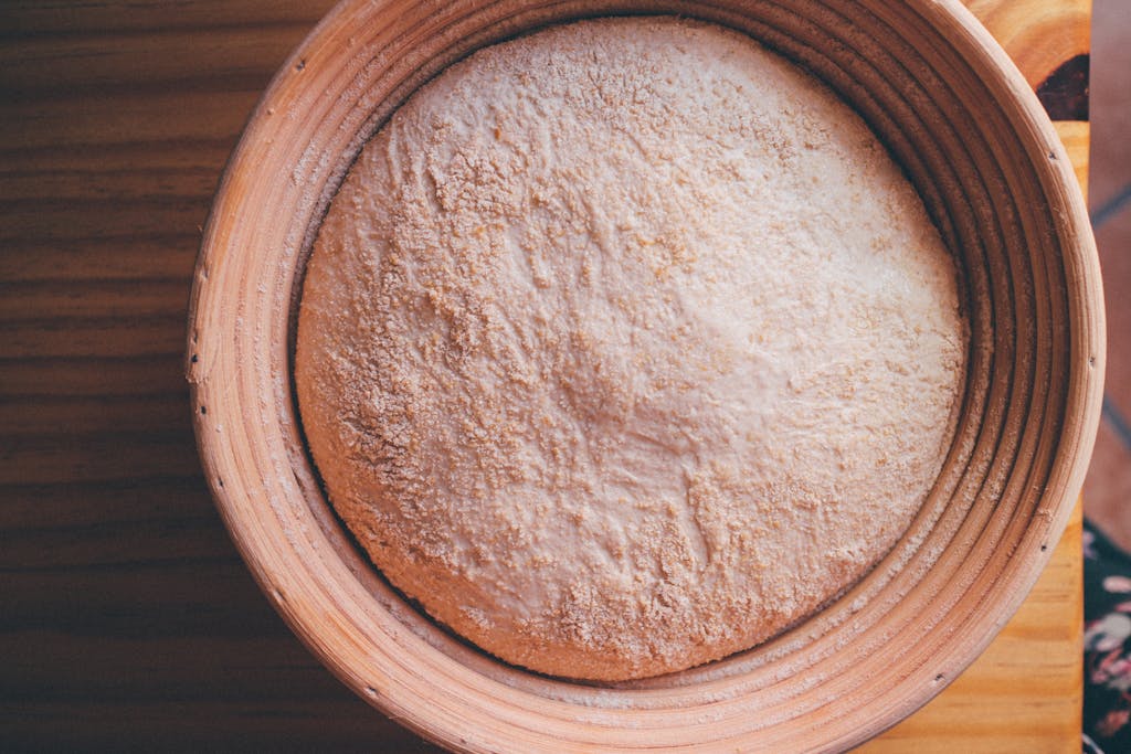 Top view of sourdough dough resting in a ceramic bowl on a wooden surface.