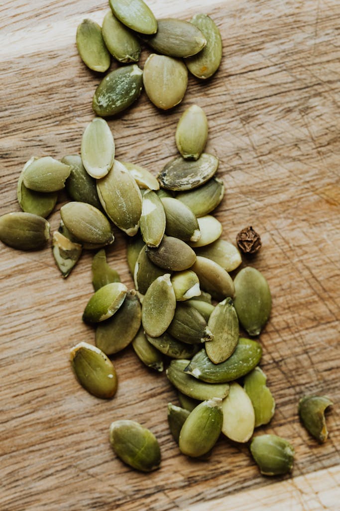 A detailed shot of green pumpkin seeds scattered on a wooden board, perfect for food blogs or healthy lifestyle concepts.