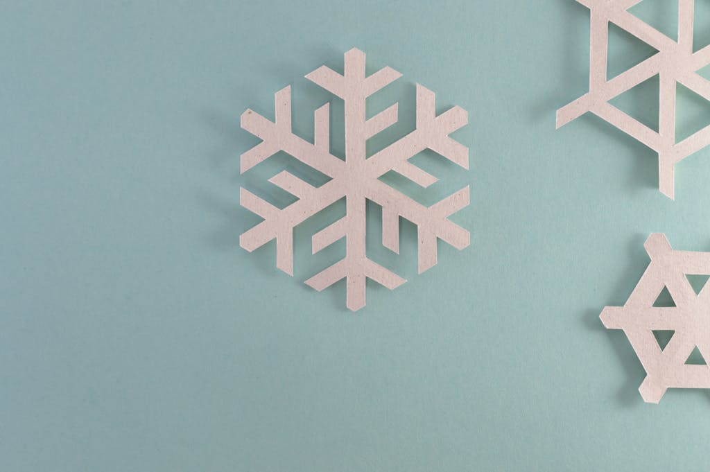 Elegant paper snowflakes on a pale blue background, perfect for winter or holiday decor.