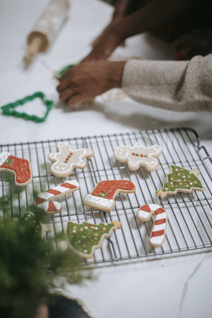 Hands decorating festive gingerbread cookies with icing for Christmas celebration.