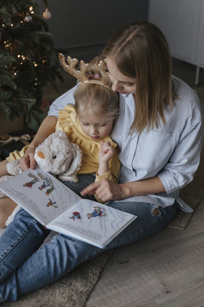 A mother and daughter bond while reading a book together with holiday decorations.